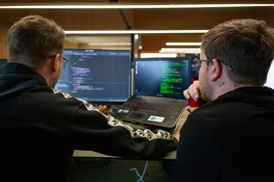 IT guys looking at a coding program on a laptop and monitor