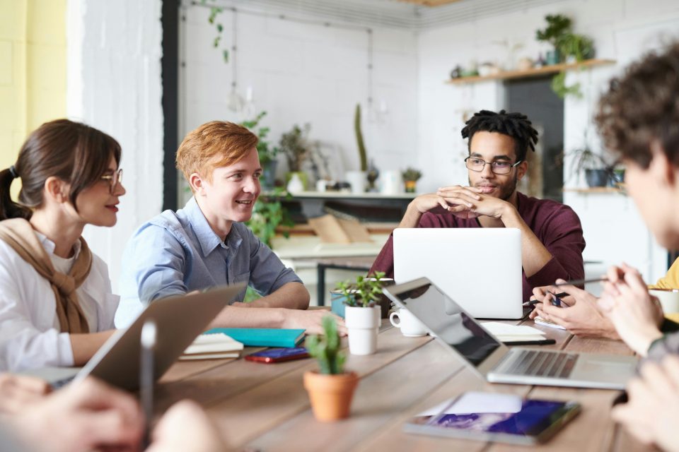 Diverse team collaborating around a table with laptops in a modern office
